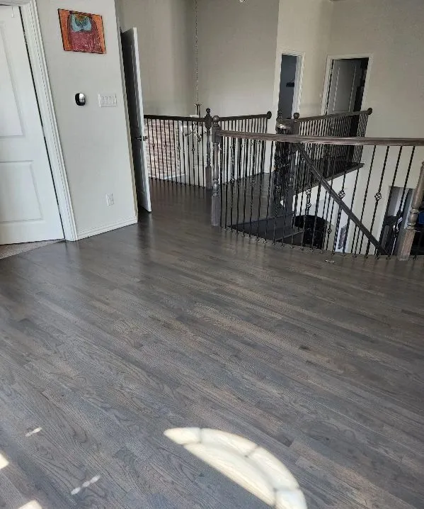 Gray-stained hardwood flooring on an upstairs landing and hallway in a Dallas Fort Worth TX home