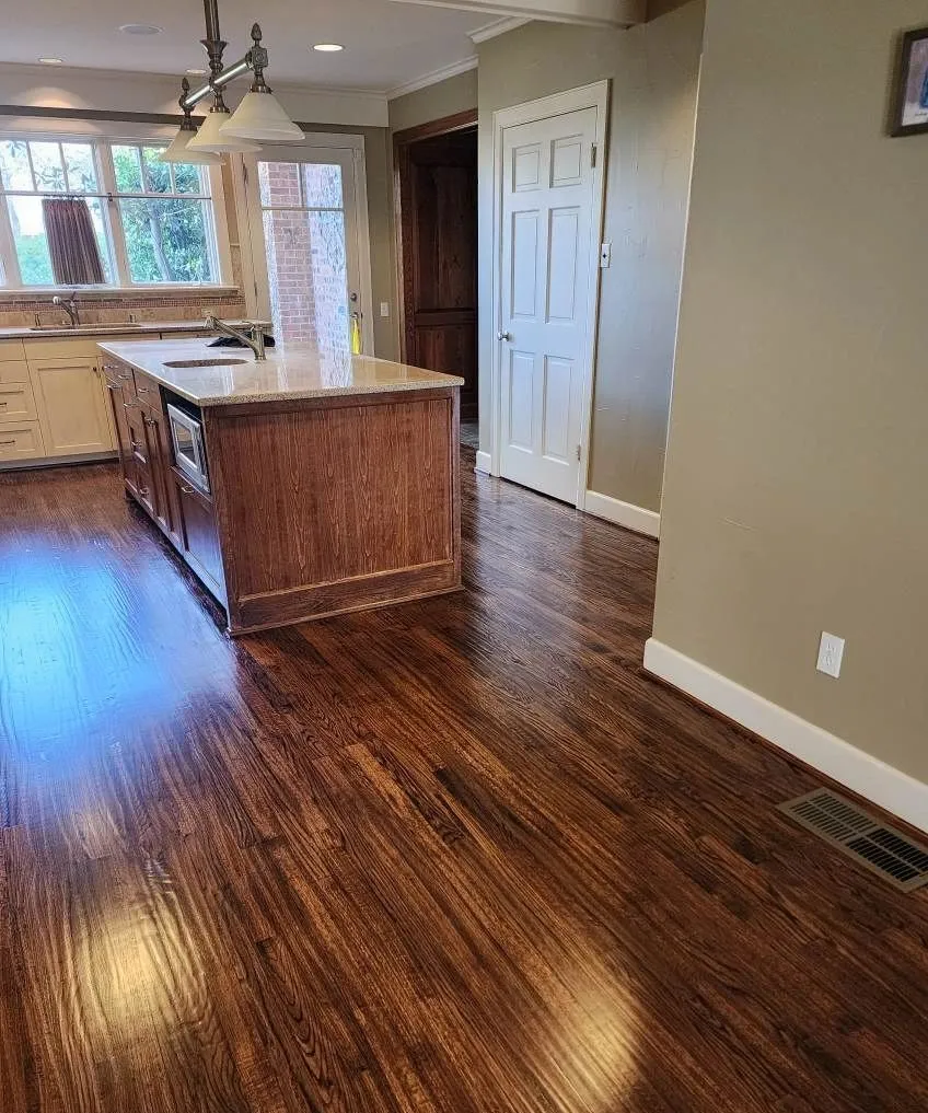 Dark stained hardwood flooring flowing into a kitchen with island in a McKinney TX remodel