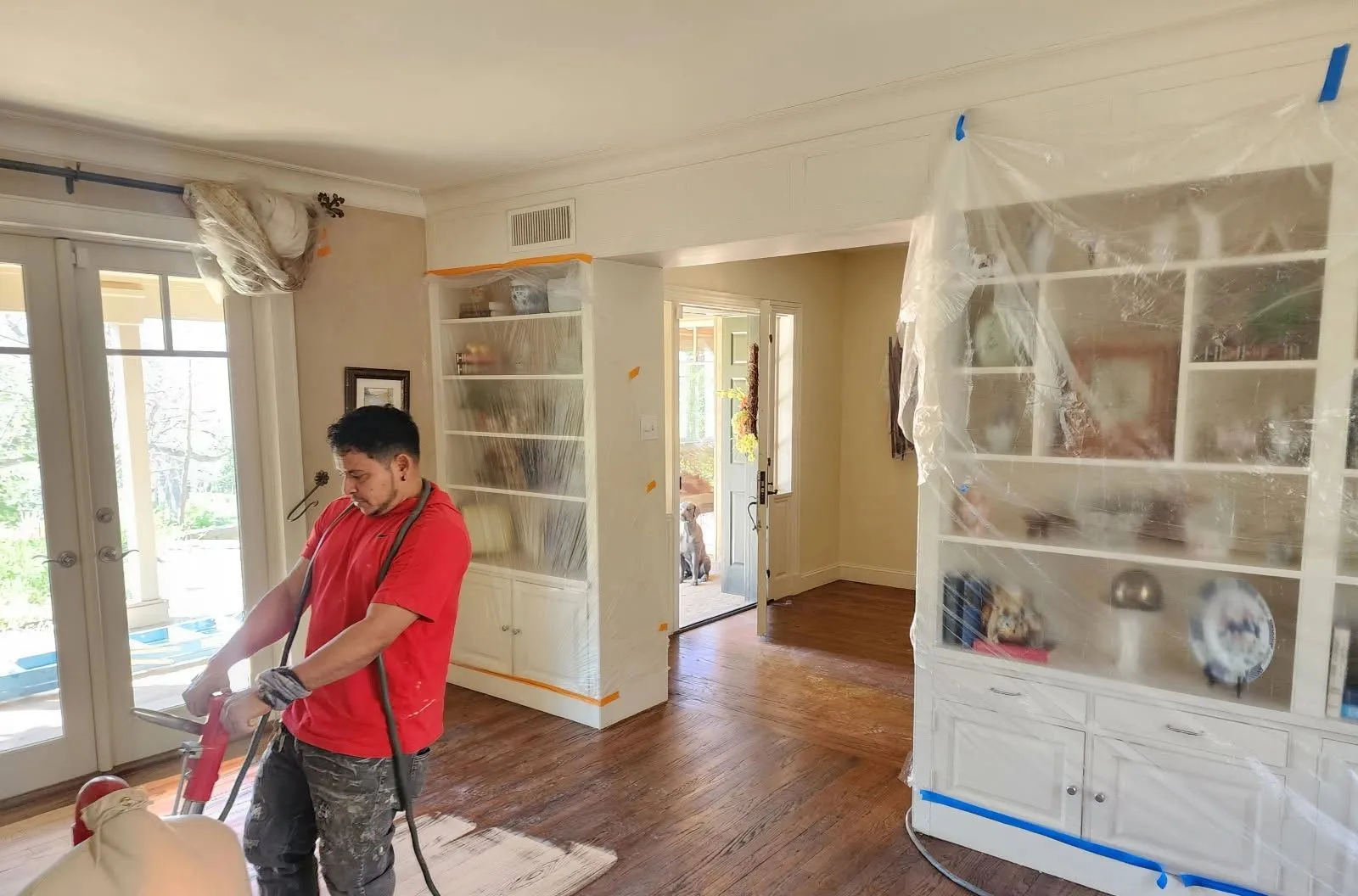 Artistry Floors craftsman sanding a hardwood floor with dust containment during a whole-home refinishing project near McKinney TX