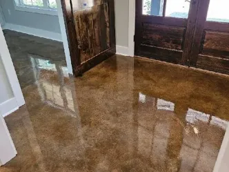 High-gloss brown acid-stained concrete entry floor reflecting the front doors of a Dallas-Fort Worth home