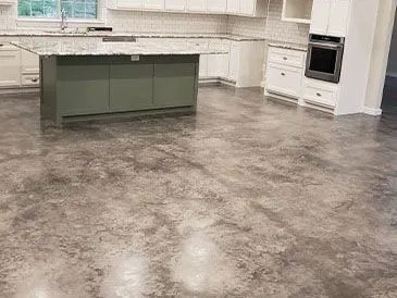 Grey acid-stained and polished concrete floor running through an open kitchen in a McKinney, TX home