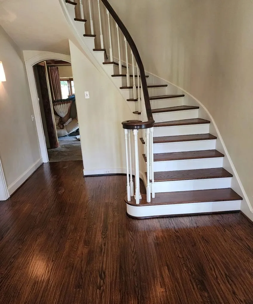 Refinished dark oak hardwood floor and staircase treads in a McKinney TX entry hall